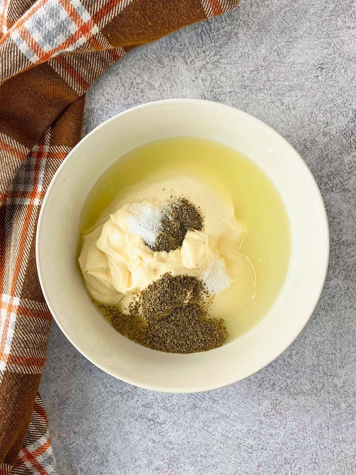 Miracle Whip, lemon juice, vinegar, sugar, and seasonings in a small white bowl.
