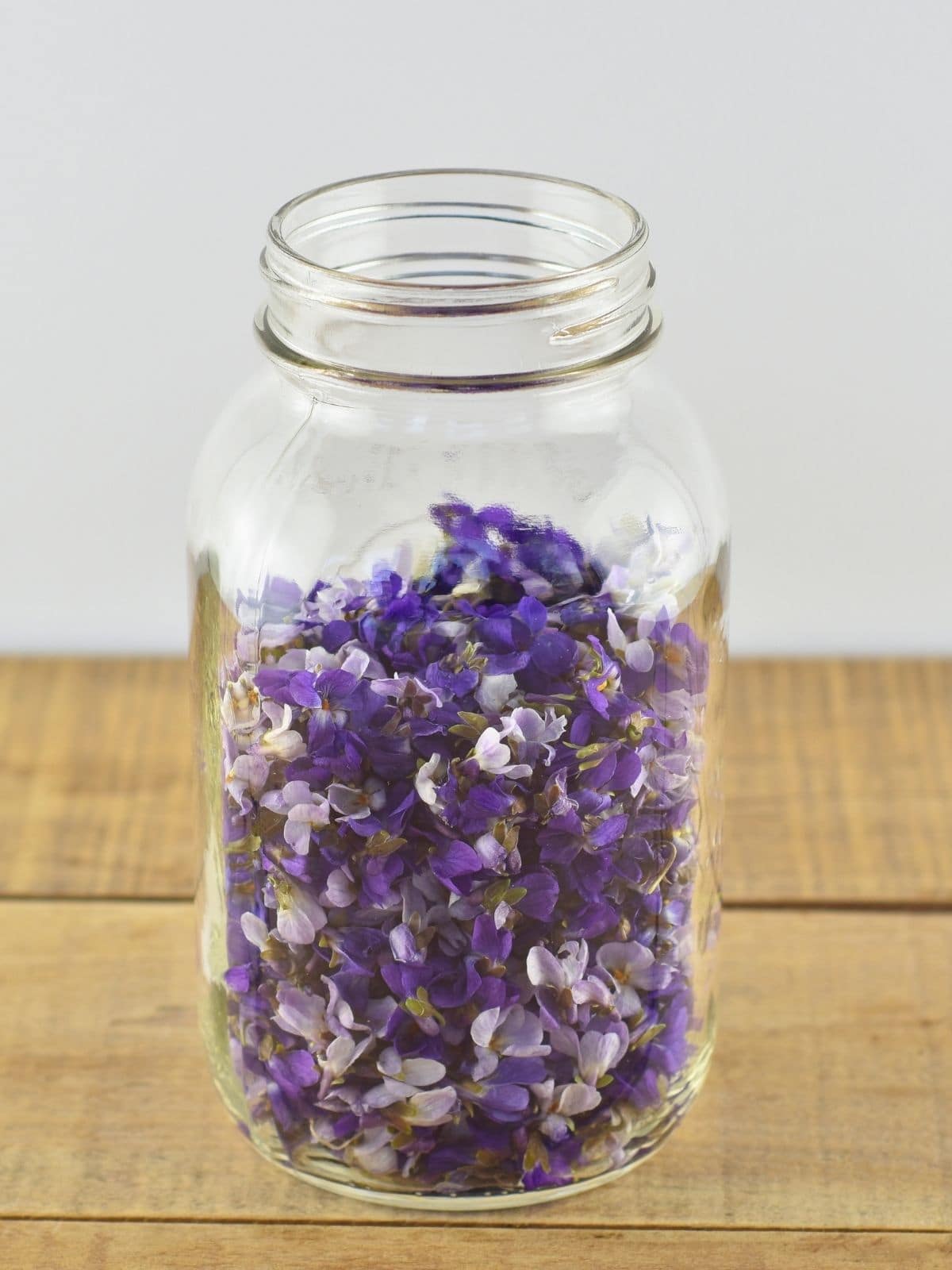 A large quart mason jar filled with purple and white violet flowers.