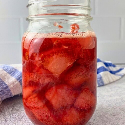 A glass jar filled with homemade strawberry compote.