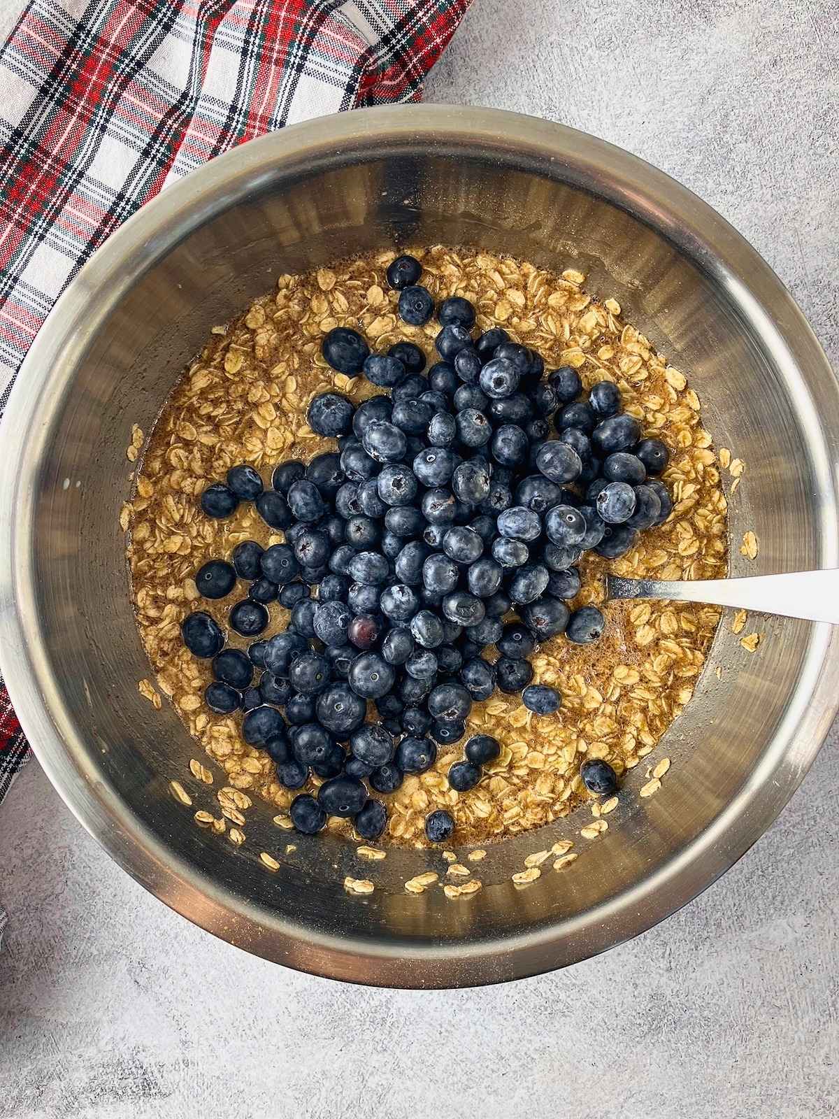 Fresh blueberries added to a bowl of mixed oats and wet ingredients for blueberry baked oatmeal.