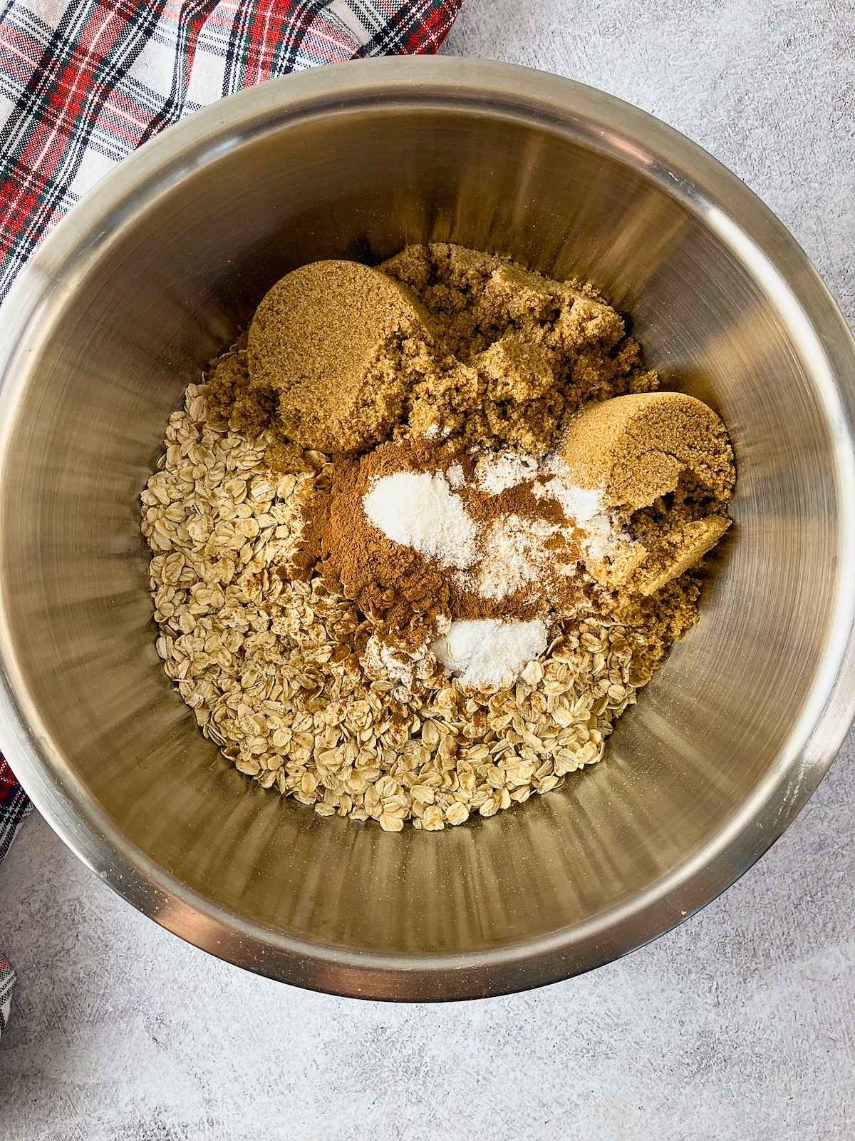 Mixing bowl with oats, brown sugar, cinnamon, baking powder, and salt ready to be stirred.