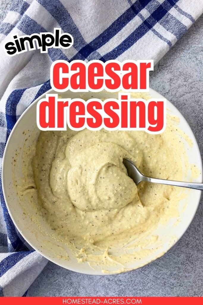 Bowl of thick Caesar dressing with a spoon resting in the creamy mixture on a gray countertop beside a blue and white checkered towel. The graphic text reads "simple caesar dressing."