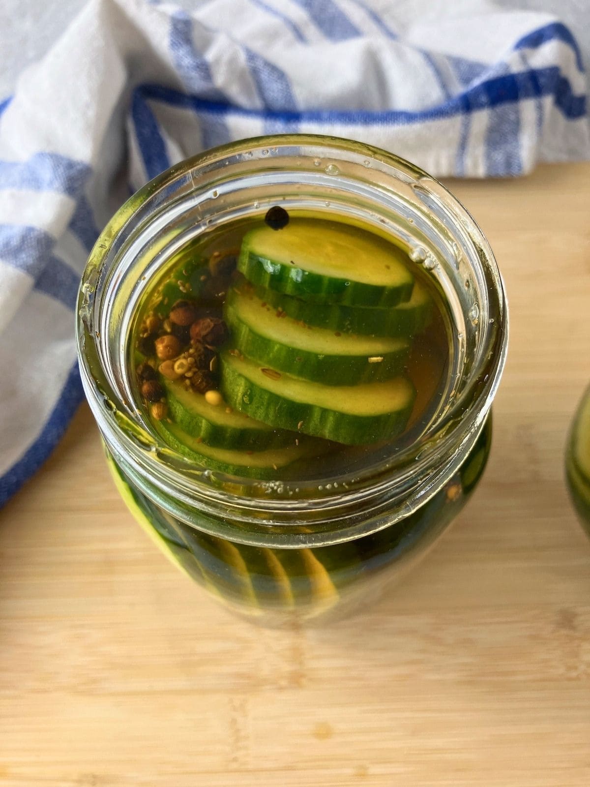 Homemade pickle brine poured over sliced cucumbers in a jar.