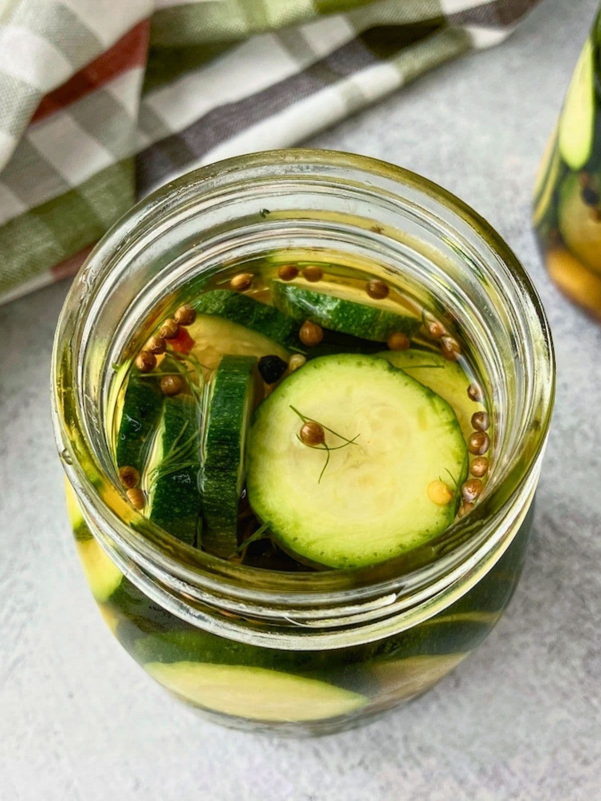 An open jar of zucchini dill pickles.