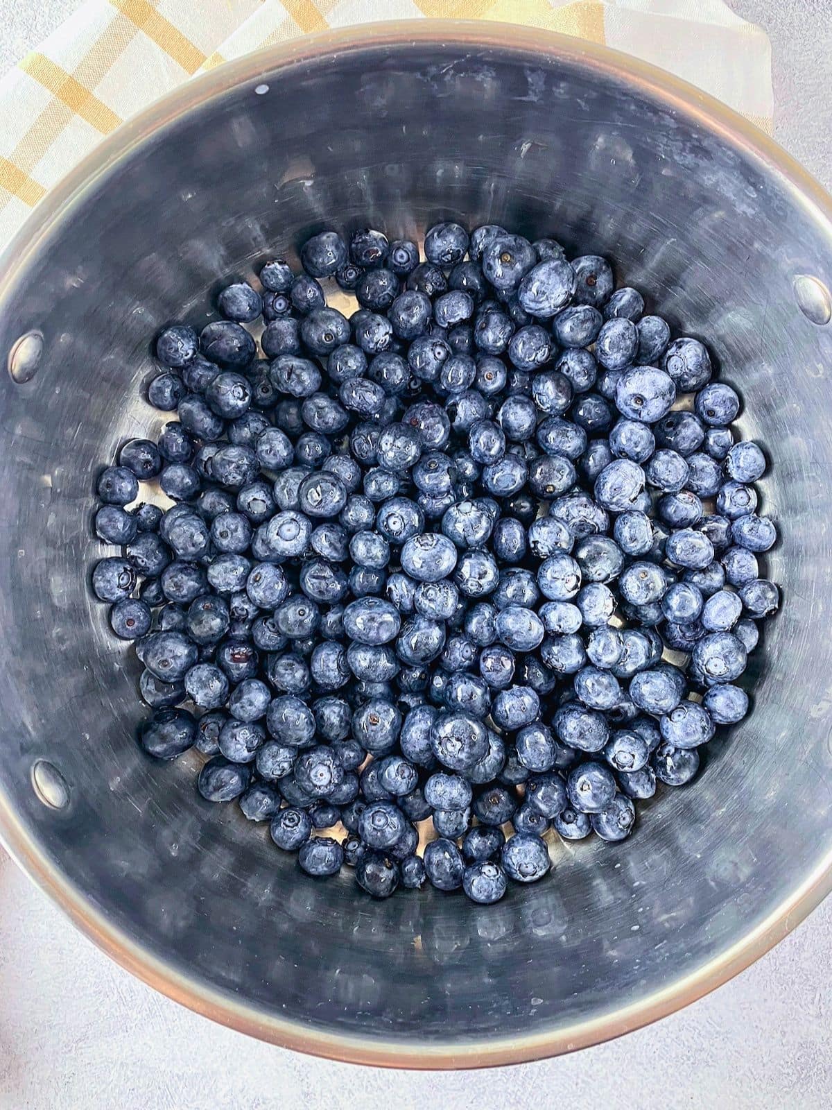 Fresh blueberries in a stainless steel pot ready to be cooked down for homemade blueberry jam.