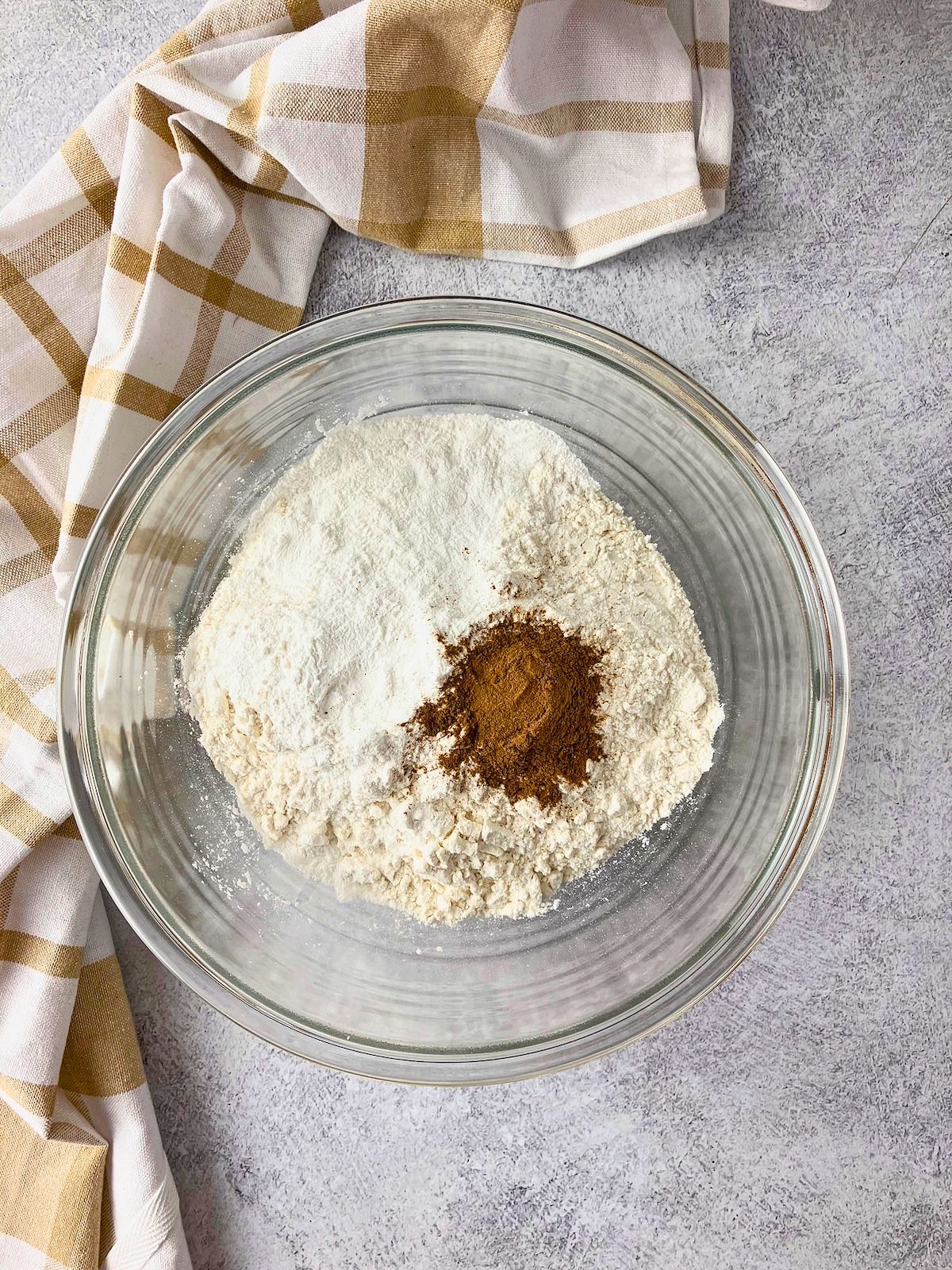 Flour, sugar, salt, baking powder, and a mound of cinnamon in a glass bowl for the blueberry cobbler topping.