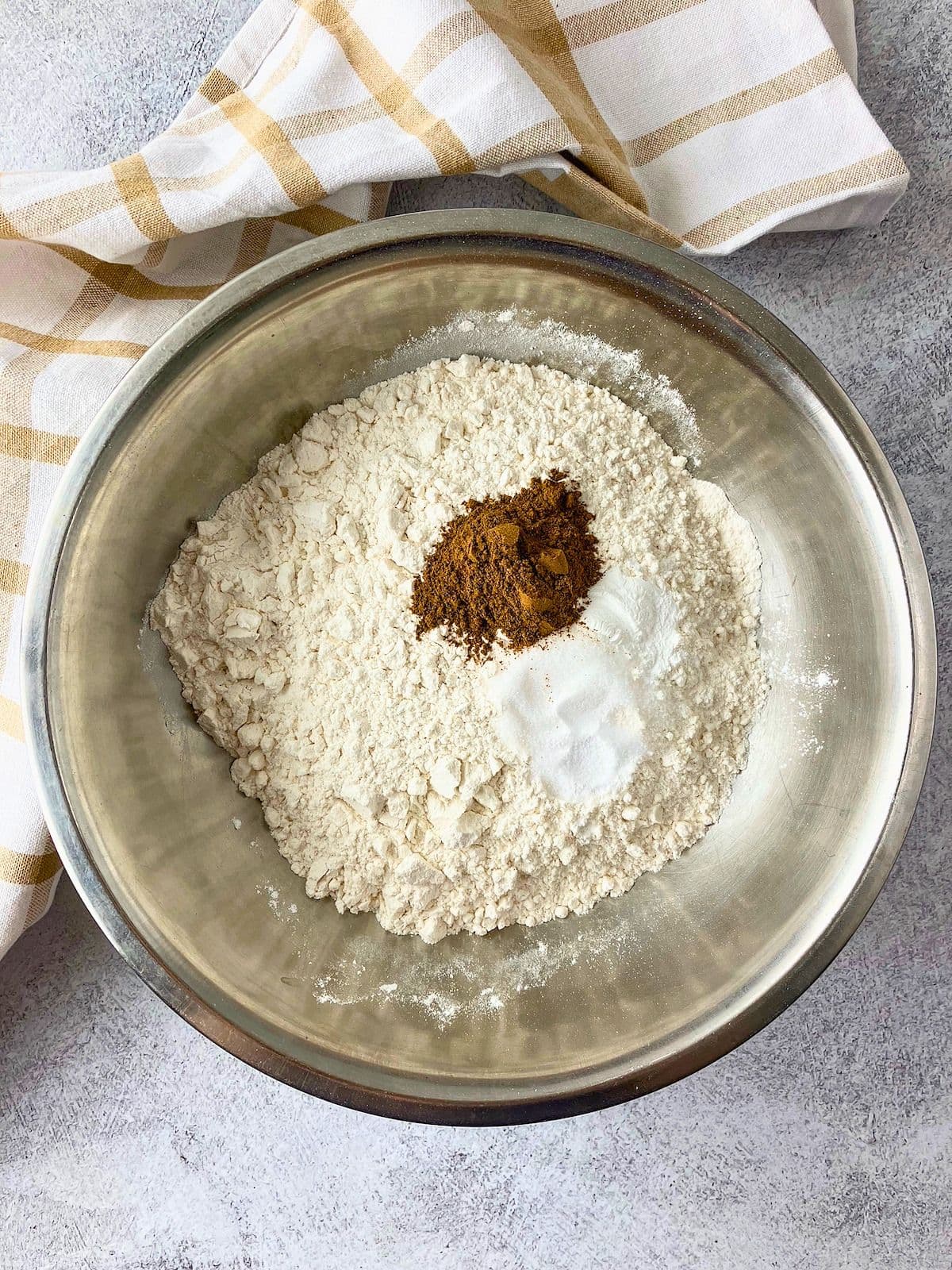 Flour, cinnamon, and leavening ingredients in a stainless steel bowl.