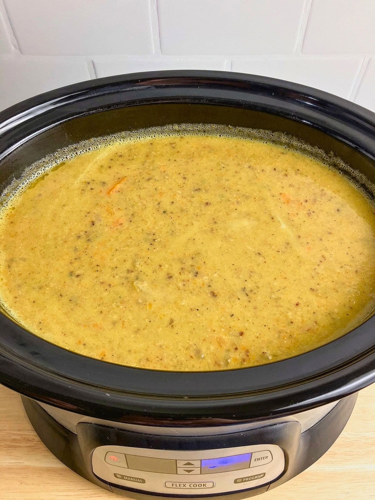 Finished slow cooker pumpkin soup with ground pork filling a black crockpot with a creamy golden texture and small pieces of meat and vegetables throughout.
